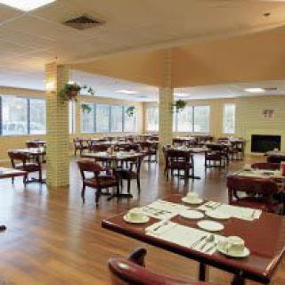 A spacious dining area with neatly arranged tables and chairs, featuring large windows that let in ample natural light.