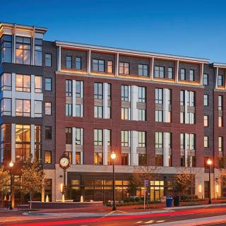 A modern multi-story apartment building illuminated at night in an urban setting.