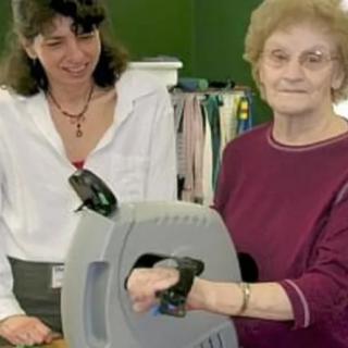 An elderly woman and a young woman interacting with a medical device.