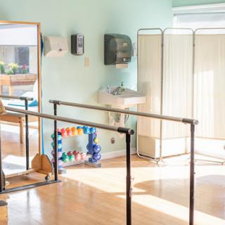 A bright and inviting physical therapy space equipped with ballet bars and fitness tools for rehabilitation.