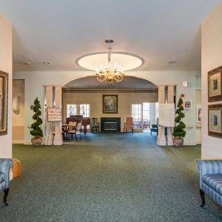 A spacious and elegantly decorated lobby area with a chandelier, furniture, and artwork.