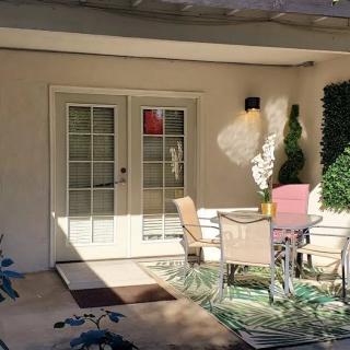 A cozy outdoor patio setup with a table and chairs, surrounded by plants and bathed in natural light.