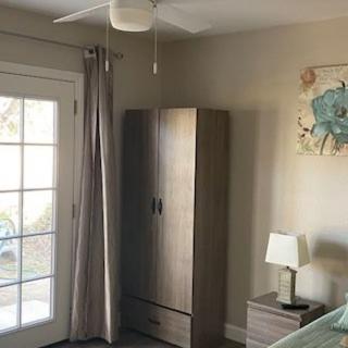 A cozy bedroom with a wardrobe, lamp, and ceiling fan next to French doors.