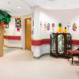 A colorful waiting area in a children's hospital adorned with vibrant wall art and an indoor plant.