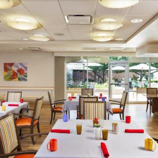 A bright and inviting dining room with neatly arranged tables, offering a view of an outdoor patio.