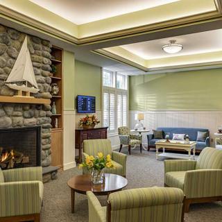 A modern living room with comfortable seating, a stone fireplace, and decorative elements including a boat model.
