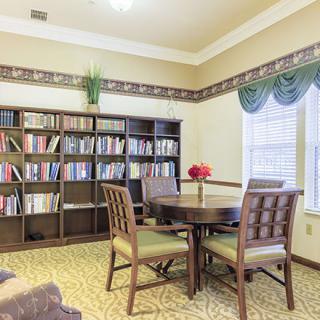 A cozy reading area with a round table and bookshelves in a well-lit room.