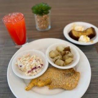 A meal consisting of fried chicken, potato salad, roasted potatoes, dessert, and a red drink.