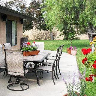A well-maintained patio with outdoor furniture surrounded by a lush garden and colorful flowers.