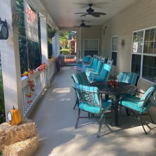 A cozy outdoor patio decorated with a fall theme, featuring a table and chairs surrounded by seasonal decorations like pumpkins and hay bales.