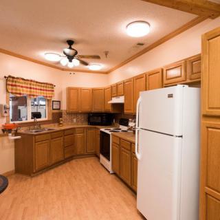 A cozy kitchen with wooden cabinets, a refrigerator, an oven, and a sink.