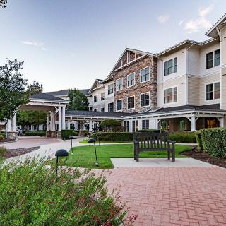 A beautiful building with manicured gardens and a brick walkway.