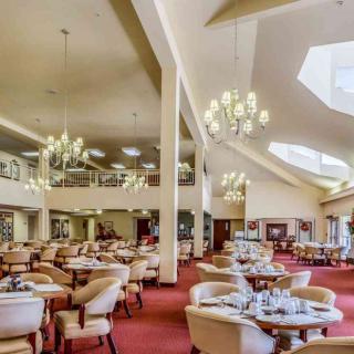 A spacious restaurant interior with elegant chandeliers and neatly arranged dining tables.