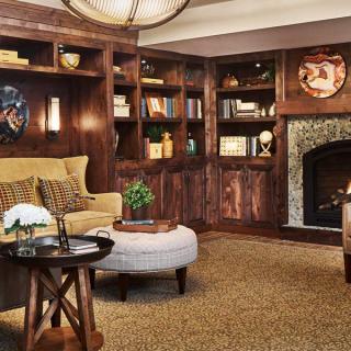 A warm and inviting living room with a fireplace, wooden shelves, and comfortable seating.