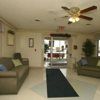 A cozy lobby area with sofas and a ceiling fan, featuring an entrance door in the background.