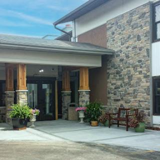 A beautifully designed entrance featuring stone and wood elements, adorned with planters and a bench.