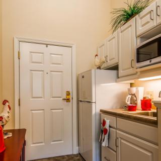A compact kitchen area with white cabinets, a microwave, and a refrigerator.