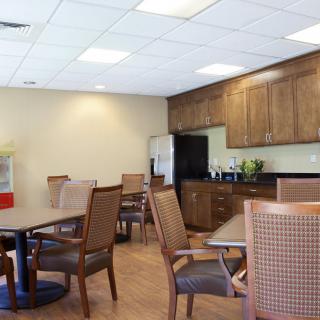 A cozy kitchen and dining area with wooden cabinets, tables, and chairs.
