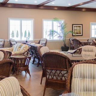 A cozy seating area with wicker furniture and decorative plants, illuminated by natural light from the windows.