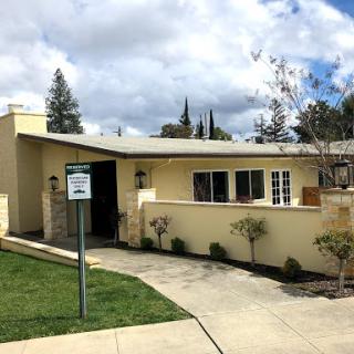 A charming single-story house with a yellow facade and well-maintained landscaping.