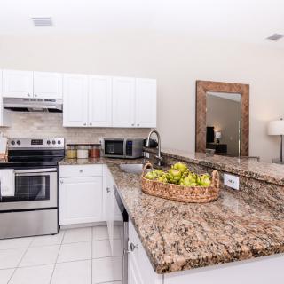 A modern kitchen with white cabinets, a granite countertop, and stainless steel appliances.