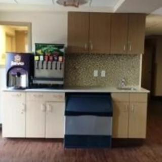 A small kitchen area with a beverage station featuring a soda machine and cabinets.