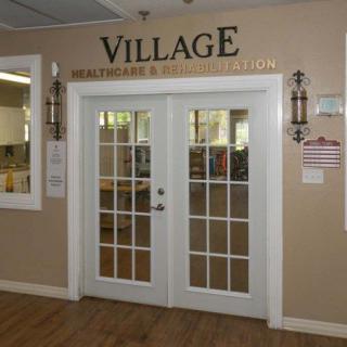 Entrance to the Village Health Care and Rehabilitation center with glass double doors.