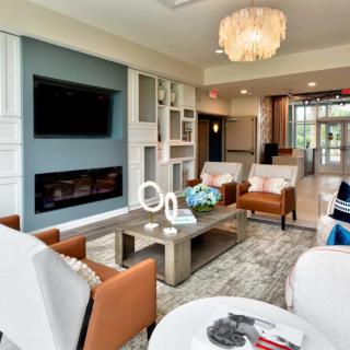 A modern living room featuring a comfortable seating area with a coffee table, wall-mounted TV, and a stylish chandelier.