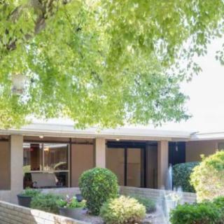 A tranquil outdoor view of a building surrounded by lush trees and shrubs.