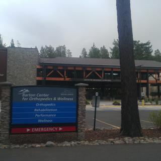 A view of a healthcare facility with a large sign, surrounded by trees on a cloudy day.