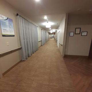 A long hospital corridor with linoleum flooring and curtains along the walls.
