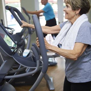 A senior woman exercises on a treadmill at the gym.