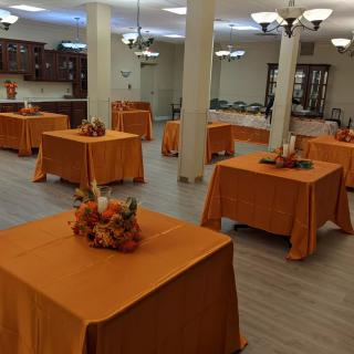 An elegantly decorated banquet hall with orange tablecloths and floral centerpieces.