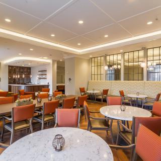 A modern restaurant interior with neatly arranged tables and chairs, featuring warm lighting and stylish decor.