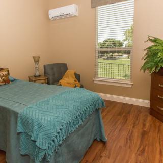 A cozy bedroom with a single bed and natural lighting through the window.