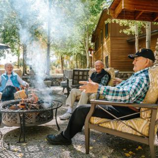 A group of people enjoying a conversation around a fire pit in an outdoor setting.