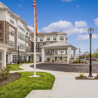 A modern residential building with a flagpole and landscaped surroundings on a clear day.