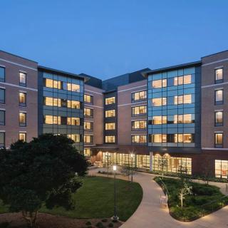 A well-lit building exterior at night with a landscaped pathway.