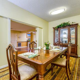 A warmly decorated dining room with a wooden table and chairs, complemented by a china cabinet.