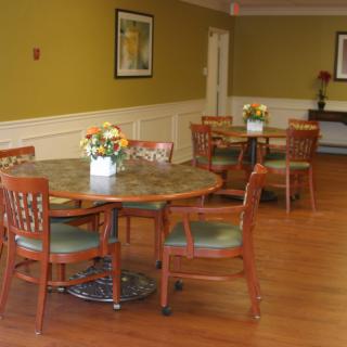 A cozy dining area with round tables and floral centerpieces.