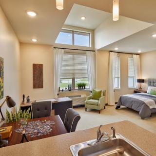 A spacious and modern bedroom with a cozy workspace, featuring bright lighting and a serene view.