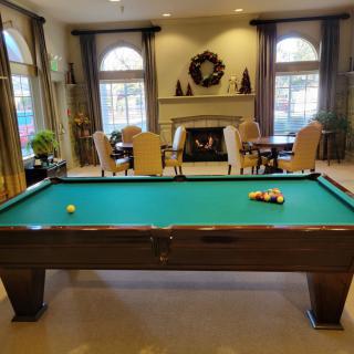 A cozy game room featuring a pool table and a fireplace, with seating arrangements for relaxation.