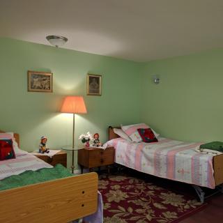 A cozy bedroom with twin beds, a lamp, and decorative wall art.