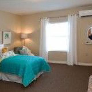 A cozy bedroom with a teal bedspread and soft lighting.