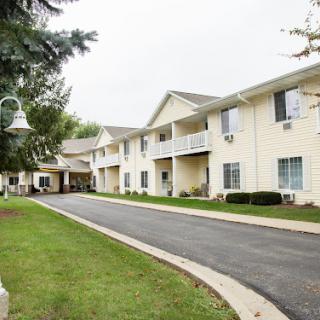 A view of a residential complex featuring two-story buildings surrounded by greenery and a paved road.