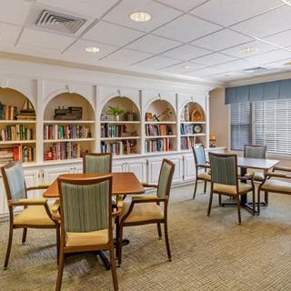 A cozy library with bookshelves, tables, and chairs arranged for reading.