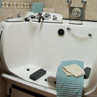 A bathroom featuring a specialized bathtub with towels placed on its edge.