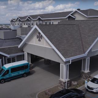 A view of a modern building with a welcoming entrance and parked vehicles.