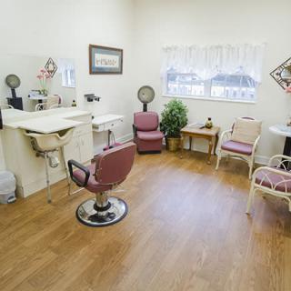 A cozy hair salon with styling chairs, a sink, mirrors, and a small waiting area.