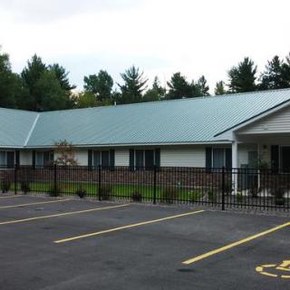 A single-story office building with a metal roof, surrounded by trees and a parking lot.